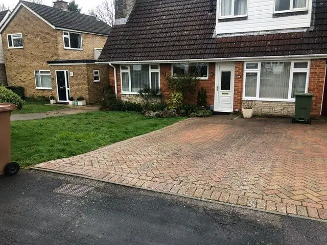 Red block paved driveway with a charcoal border in front of a semi-detached house