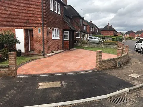 Red clay paver front patio enclosed by a low brick wall