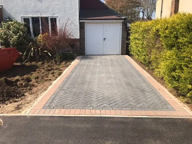 Herringbone block paved driveway with a charcoal border leading to a garage