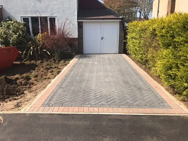 Herringbone block paved driveway with a charcoal border leading to a garage
