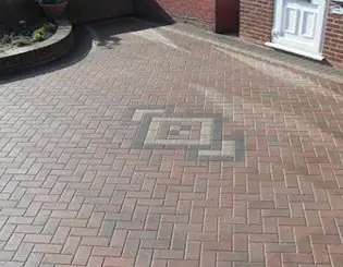 Red herringbone block paving with a grey diamond feature by a front door