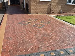Red herringbone block paving with a patterned border and feature detail
