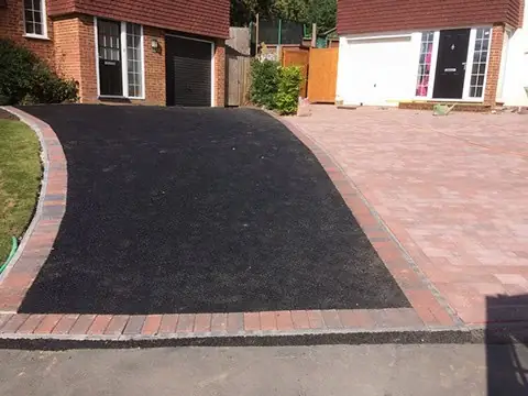 Curved tarmac driveway section meeting red block paving outside a house