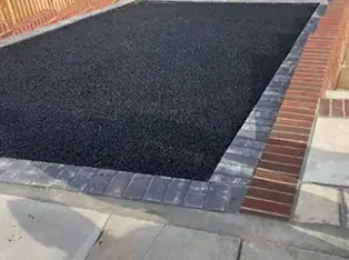 Tarmac driveway edged with red and grey block paving